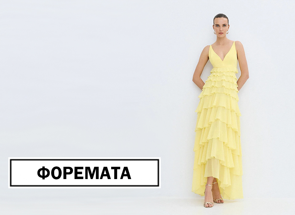 Model in a pale yellow tiered evening gown standing against a white wall sign reads ΦΟΡΕΜΑΤΑ DRESSES