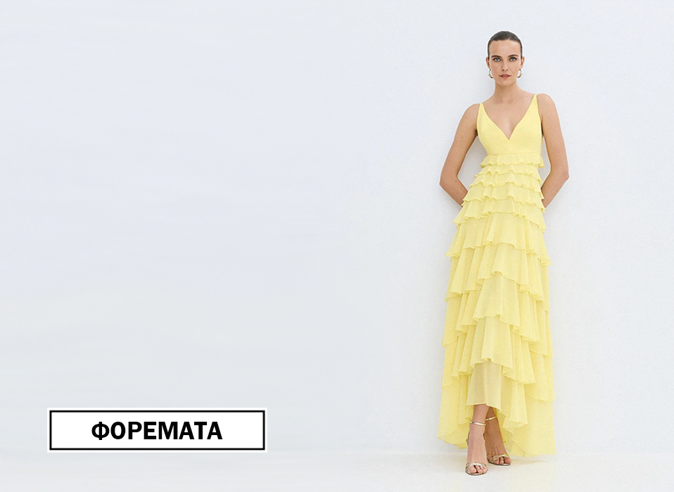 Model wearing a yellow layered ruffle gown stands against a light wall bottom left label reads ΦΟΡΕΜΑΤΑ